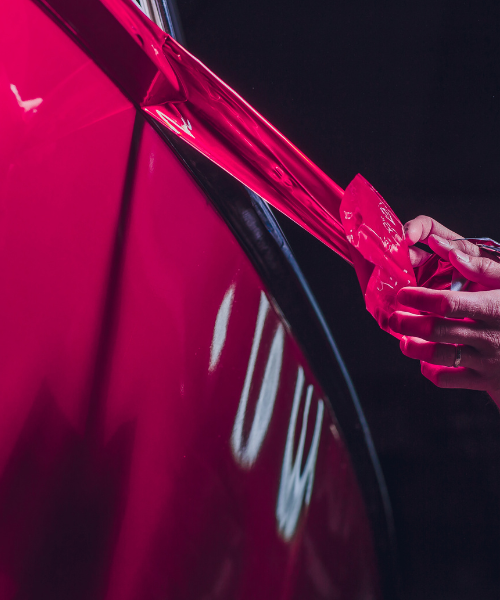 A person is opening the door of a red car