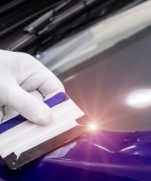 A person in white gloves polishing the hood of a blue car