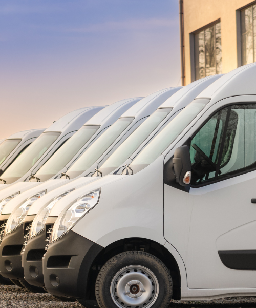 A row of white vans parked next to each other