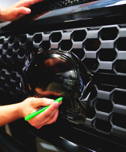 A person putting a green marker on the grill of a car